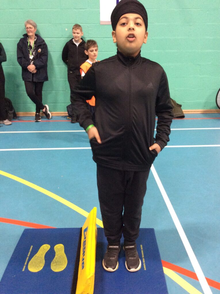 A young boy is pictured looking at the camera whilst in position to jump from side-to-side on a mat as part of the School Games contest.