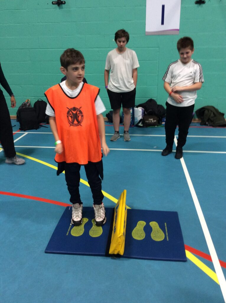 A boy is pictured with his peers in the sports hall, about to participate in the side-to-side bench jumps.