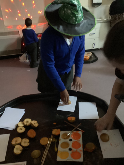 A young girl is seen creating some artwork using craft materials, whilst wearing a Witch's hat for Halloween.
