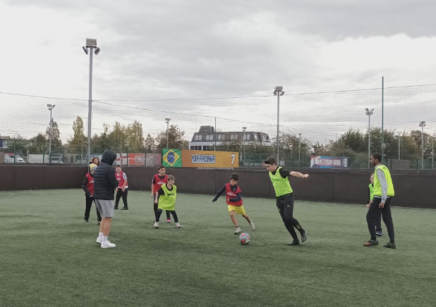 Milestone Academy students are pictured playing a game of Football together on a field at Sports Club.