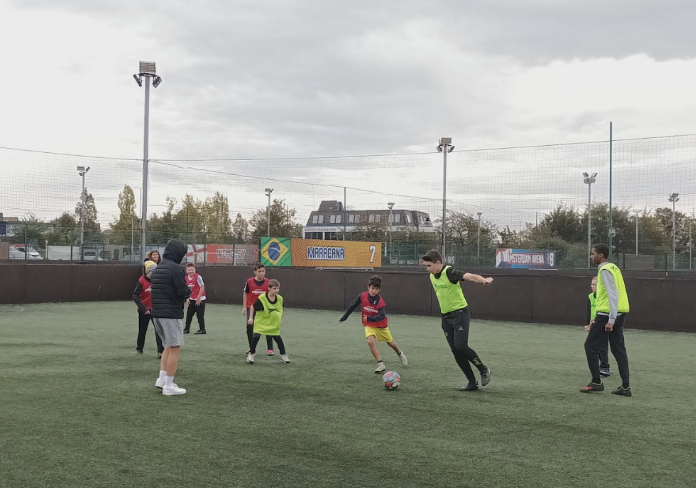 Milestone Academy students are pictured playing a game of Football together on a field at Sports Club.