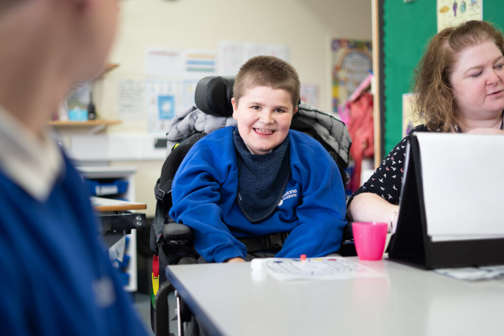 A young boy in a wheelchair smiling at the camera