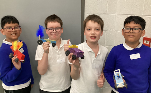 4 students smiling for a photo holding up their projects