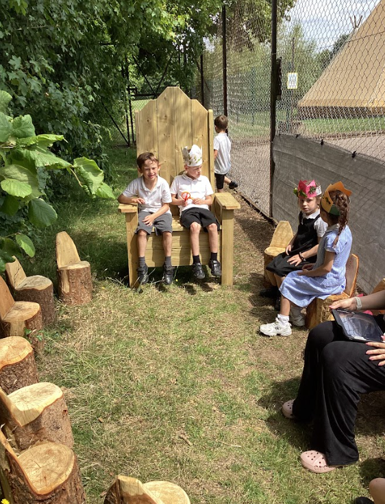 Pupils sitting in the wooden fairy circle, Three are wearing paper crown hats