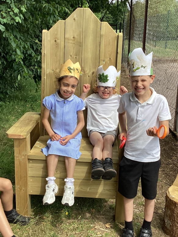 Three young pupils wearing paper crowns in the fairy circle