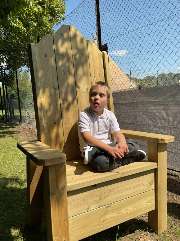 One young pupil sitting crossed legged on the wooden throne in the fairy circle