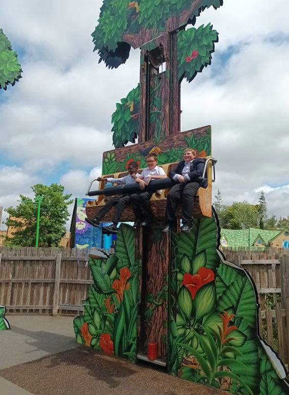 children on a "drop tower" type ride that resembles a tree trunk with jungle-themed decorations