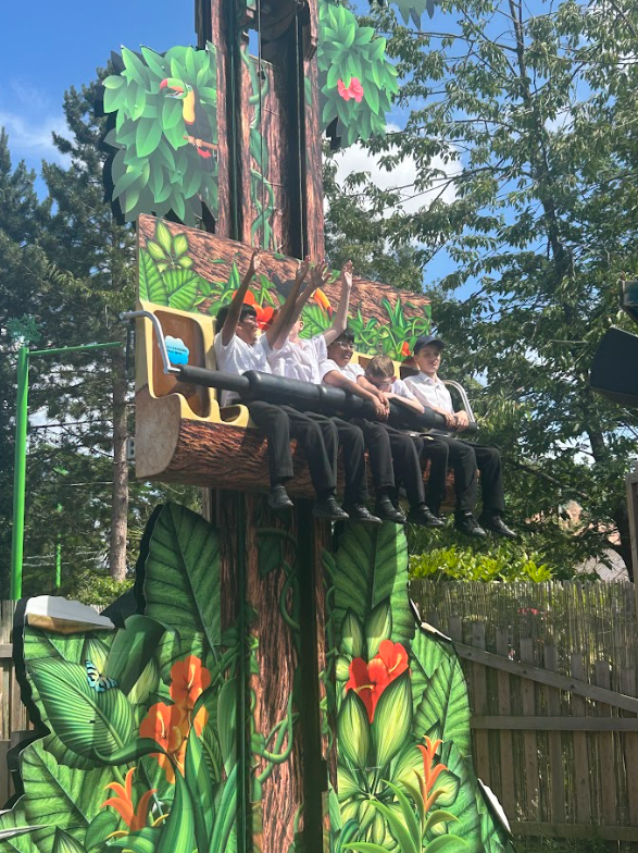 children on a "drop tower" type ride that resembles a tree trunk with jungle-themed decorations.