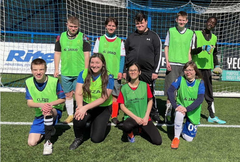 A children's football team pose for a team picture in front of a goal